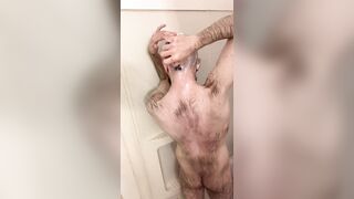 Very hairy skinny blue-eyed white guy shaves his head in the showet